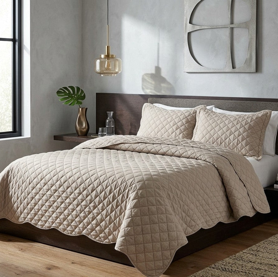 A quilted beige bedding set with a matching comforter and two shams, styled on a bed with a dark wood headboard in a modern bedroom setting.