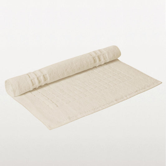 Ivory cotton bath mat with textured pattern on white background