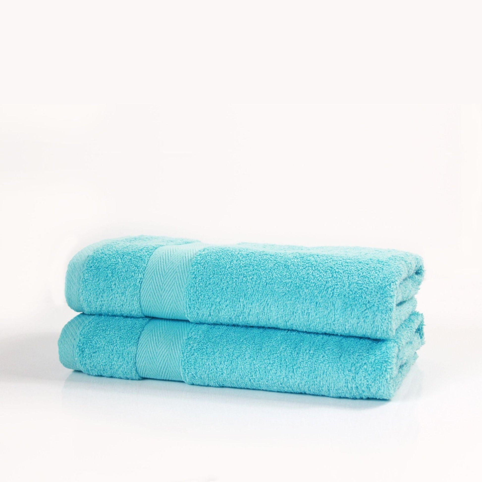 Two turquoise bath towels made from combed cotton in a thick GSM finish stacked on a white background