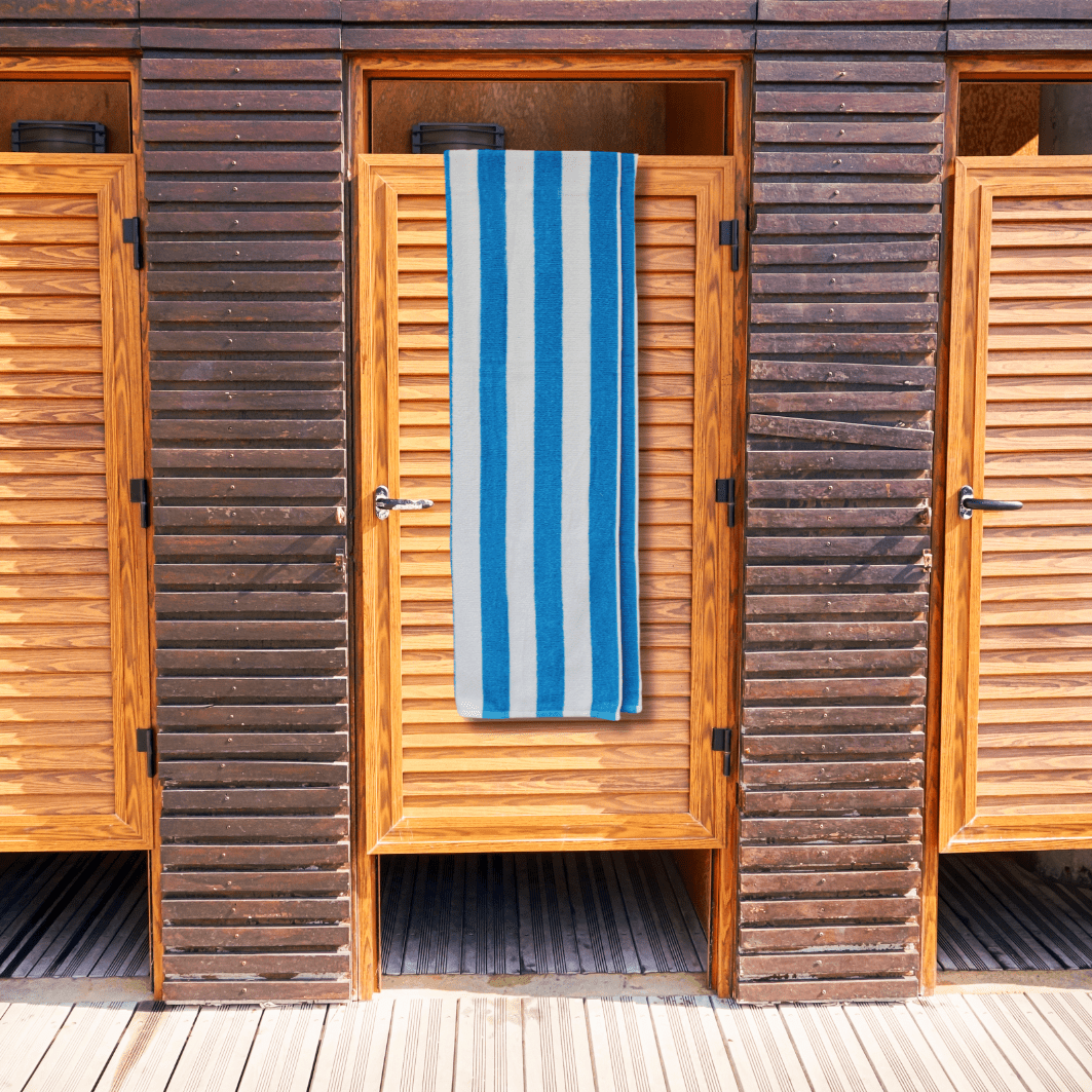 Wooden beach hut with a blue and white striped beach towel towel hanging on the door.