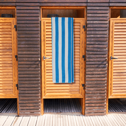 Wooden beach hut with a blue and white striped beach towel towel hanging on the door.