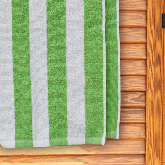 Bright green and white striped beach towel hanging on a changing room door.