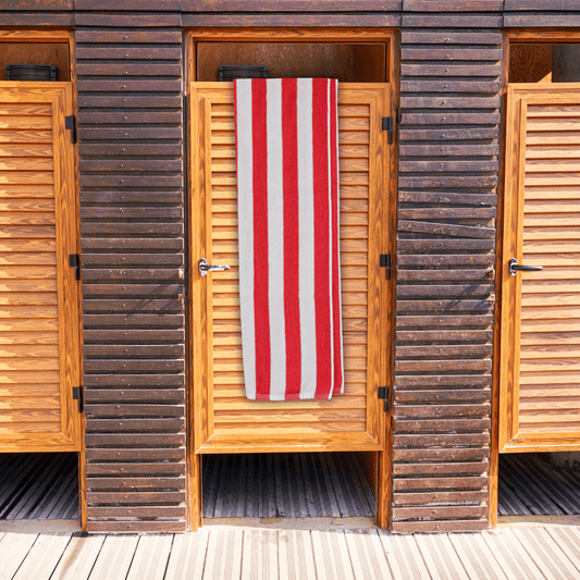 Wooden beach hut with a red and white striped towel hanging on the door.
