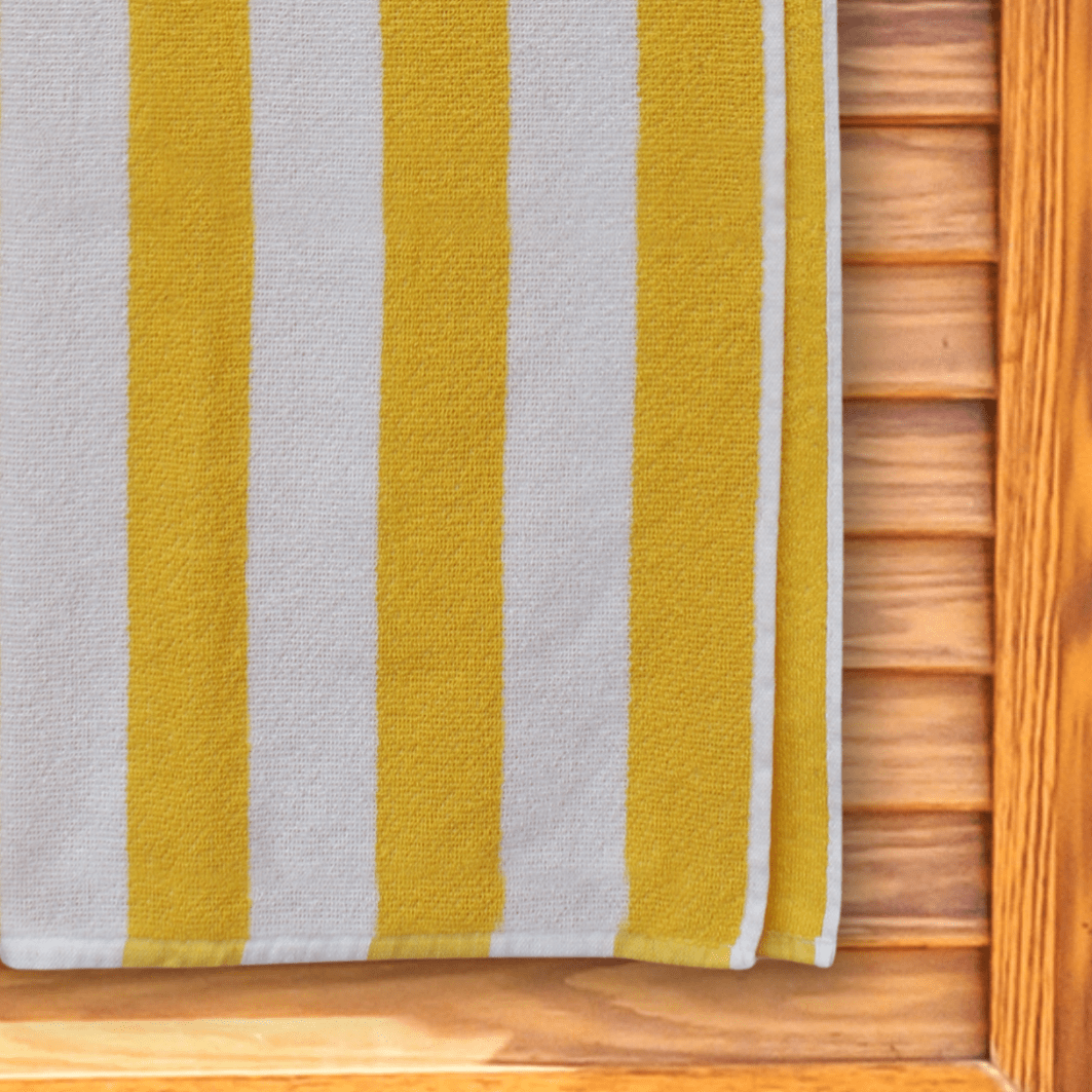 Yellow and white striped beach towel hanging on a changing room door.