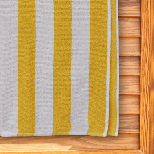 Yellow and white striped beach towel hanging on a changing room door.