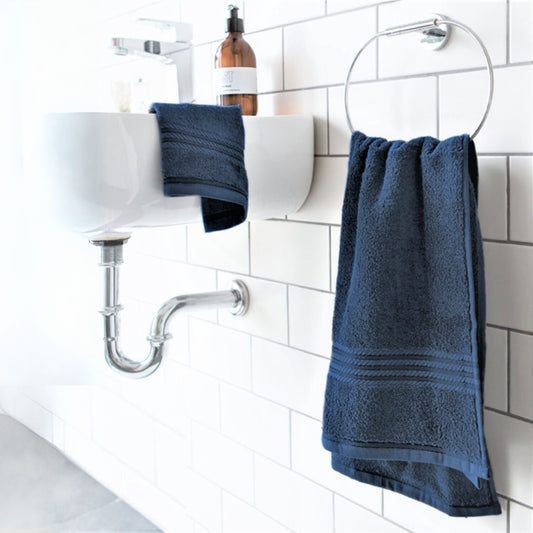 500 gsm Navy Blue cotton bath towel hanging over a sink with white tiles in the background
