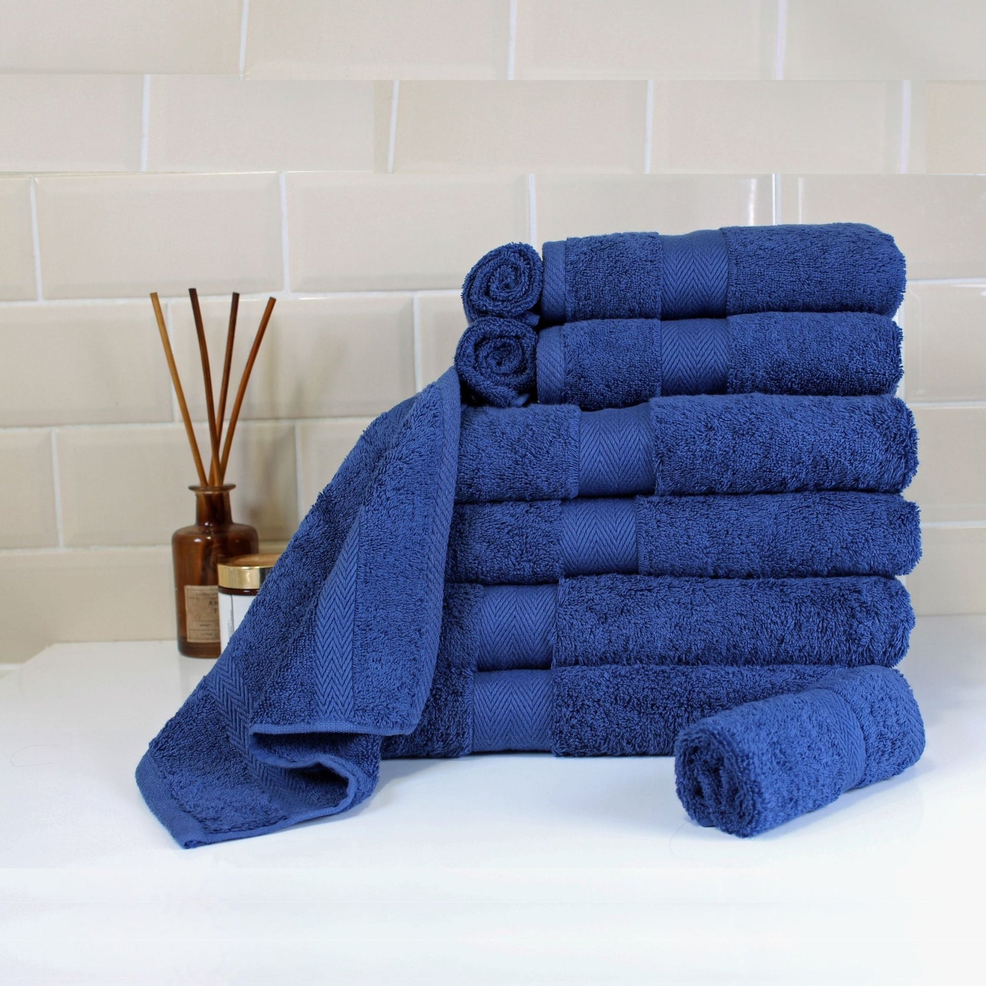 Set of Navy Blue bath towels made from fine combed cotton with thick 600 GSM pile with luxury bathroom background.