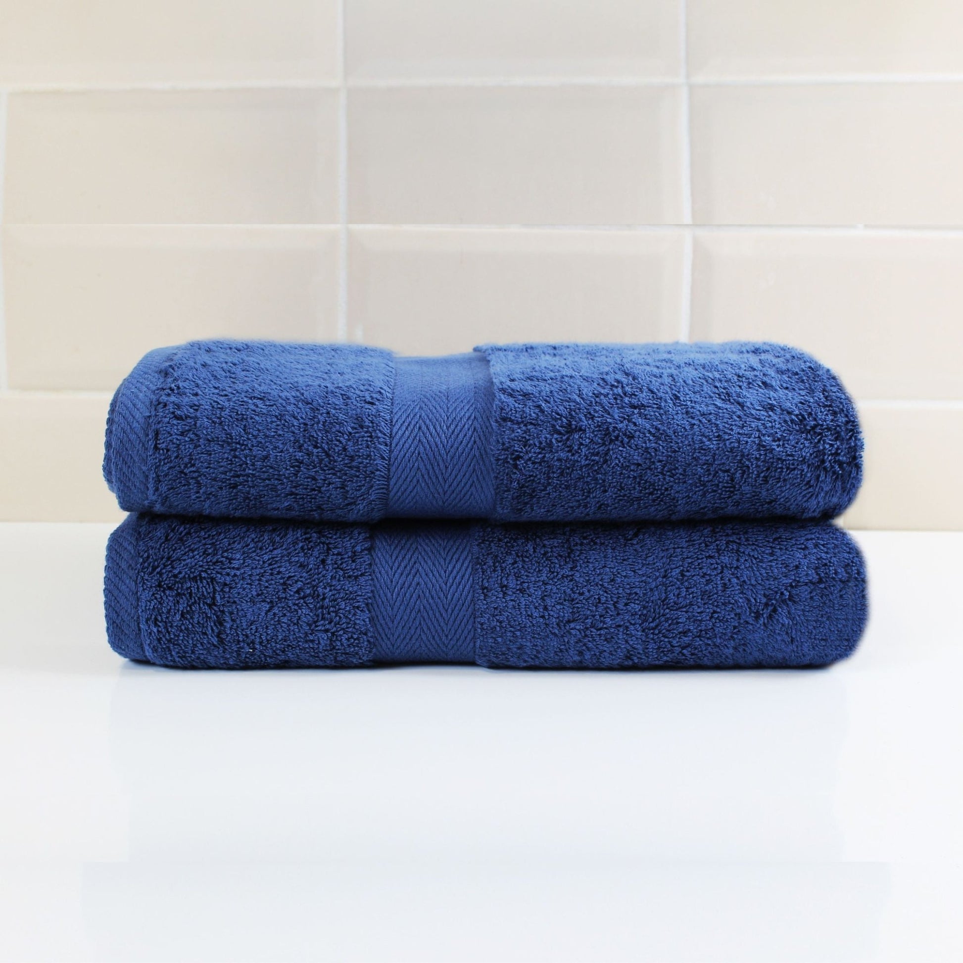 Pair of Navy Blue luxury bath towels in a luxury bathroom setting, made from fine combed cotton and 600 GSM thickness 