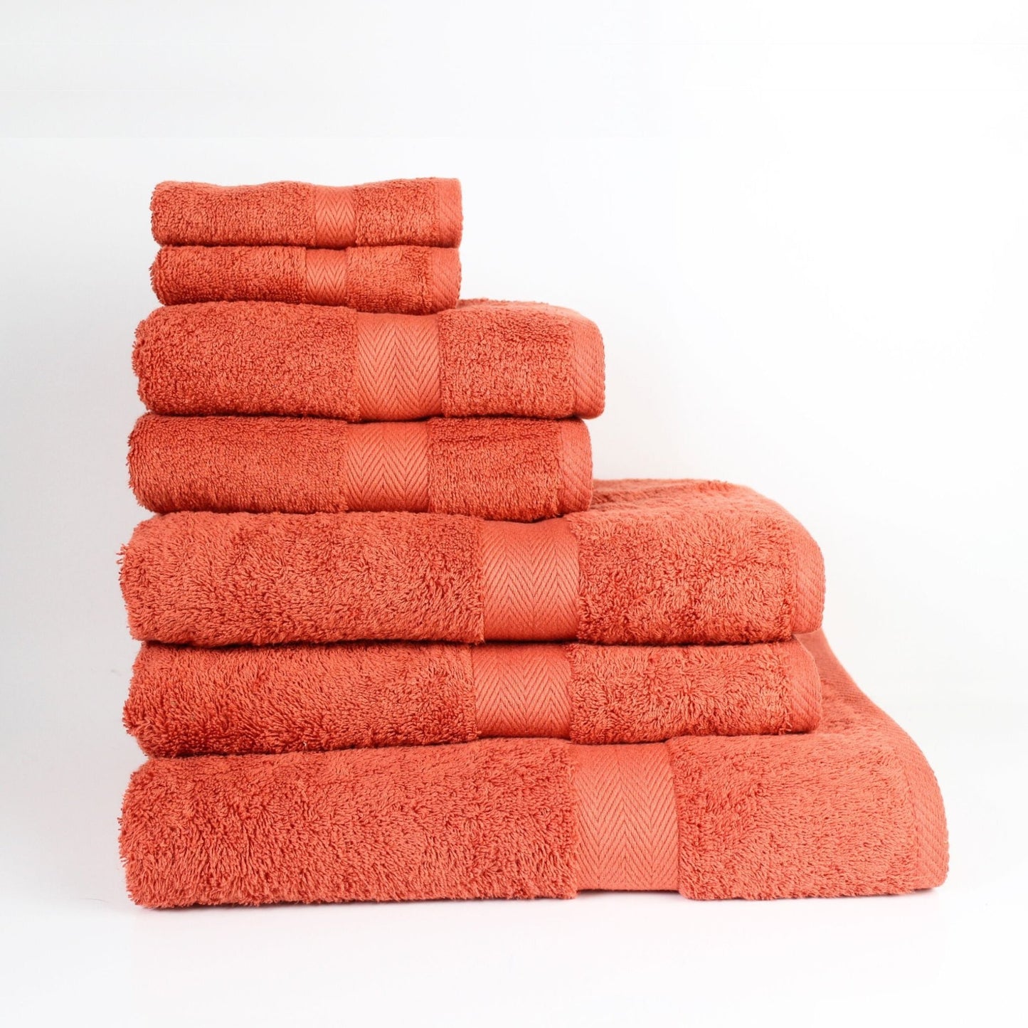 Stack of luxury bathroom towels in Paprika, made from soft fine combed cotton in a thick 600 GSM finish on a white background. 