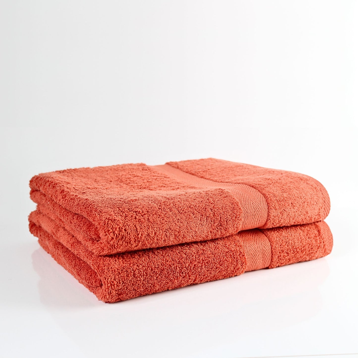 Two orange burnt orange bathroom towels on a white background