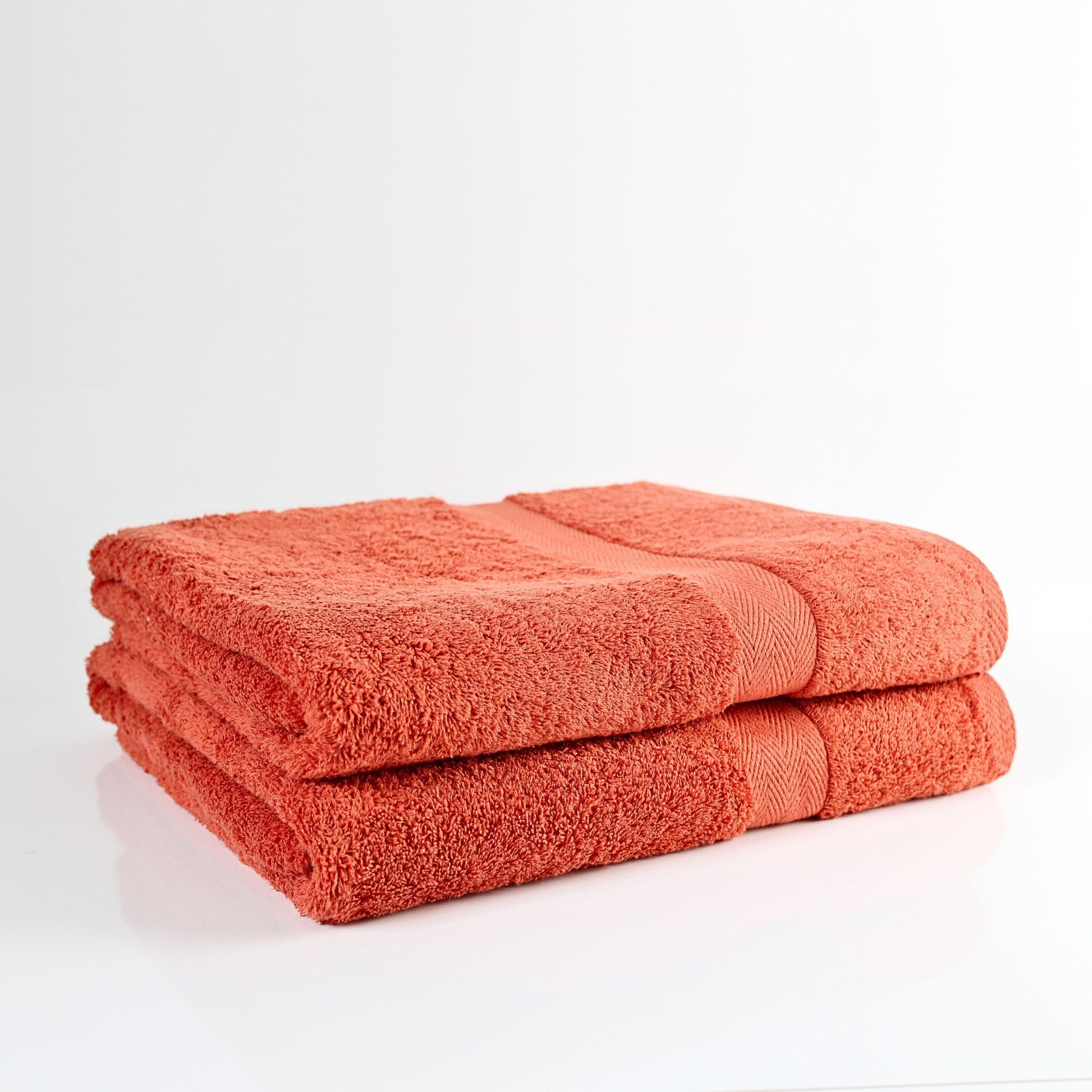 Two orange burnt orange bathroom towels on a white background