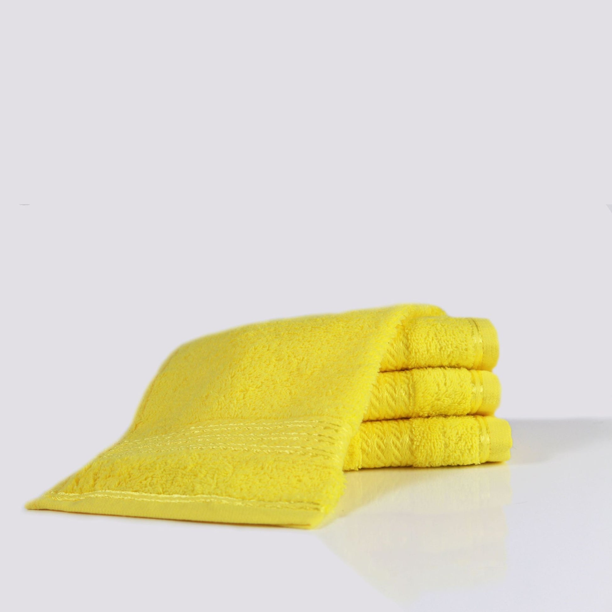 Yellow face towel on a white surface with a light grey background