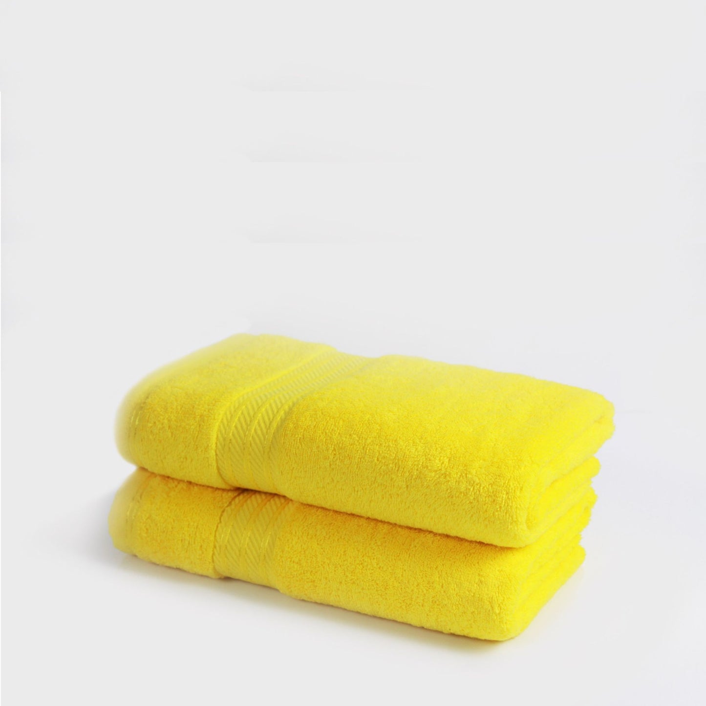 Two yellow bath towels stacked on a light gray background