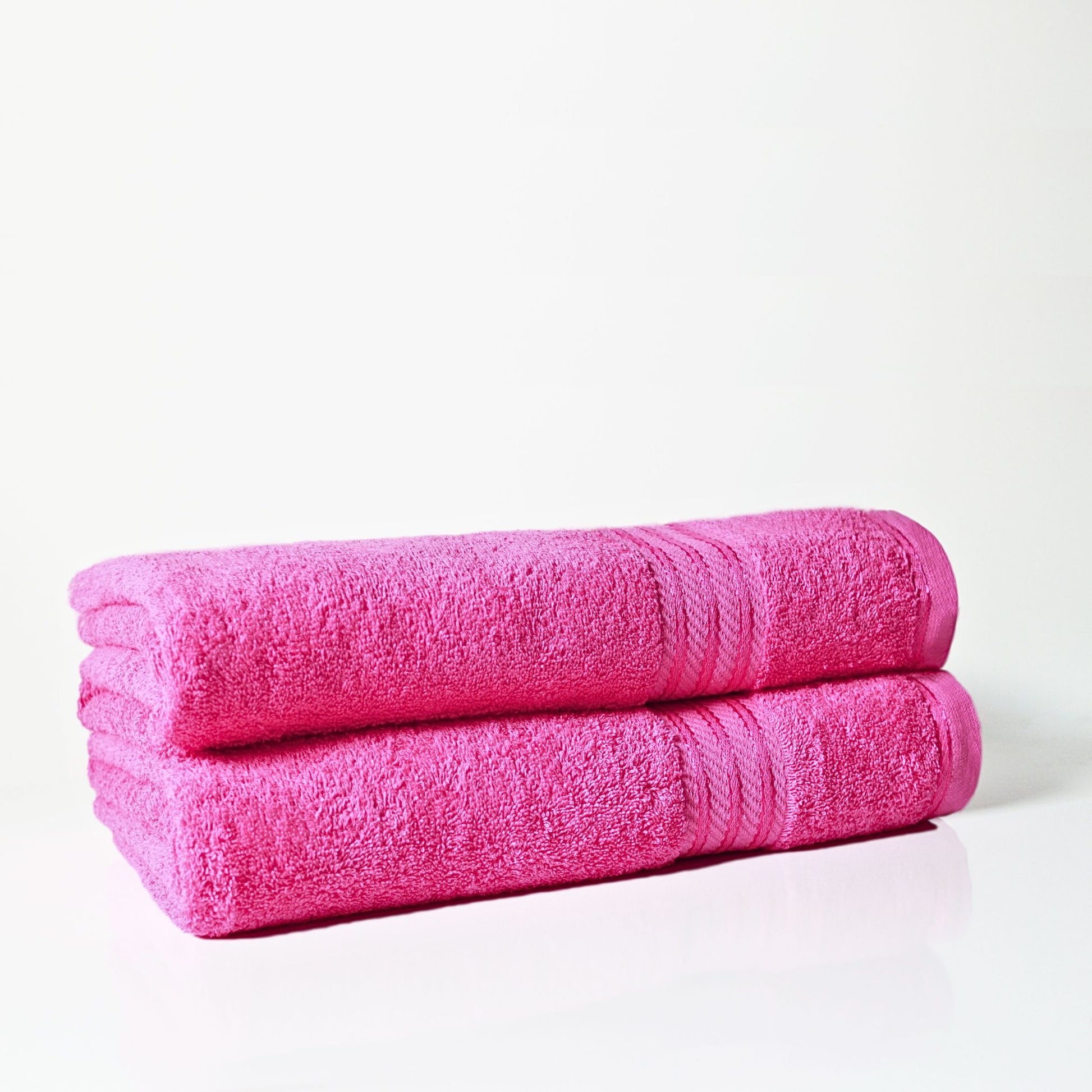 Two pink bathroom towels stacked on a white background