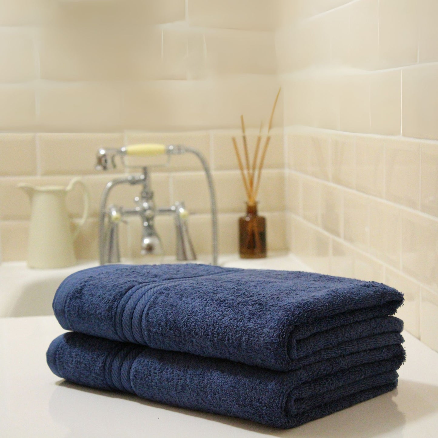 Stack of blue towels on a bathroom counter with tiled wall in the background