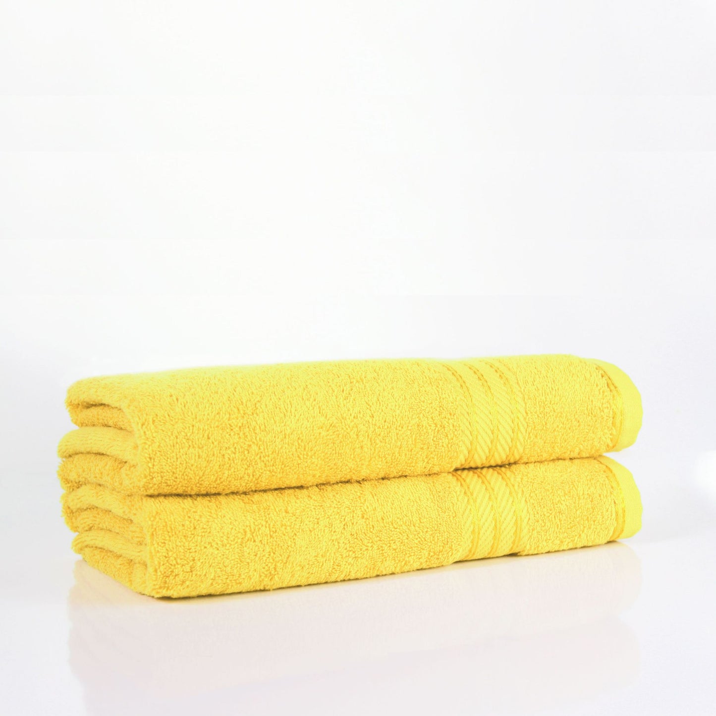 Two yellow bath towels stacked on a white background