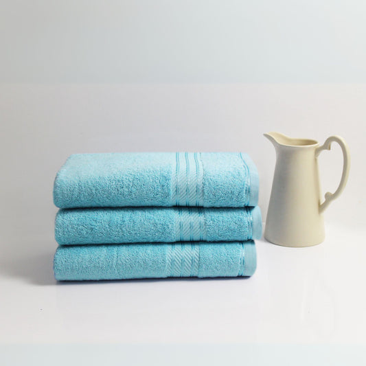 Three blue towels stacked with a white pitcher on a light grey background