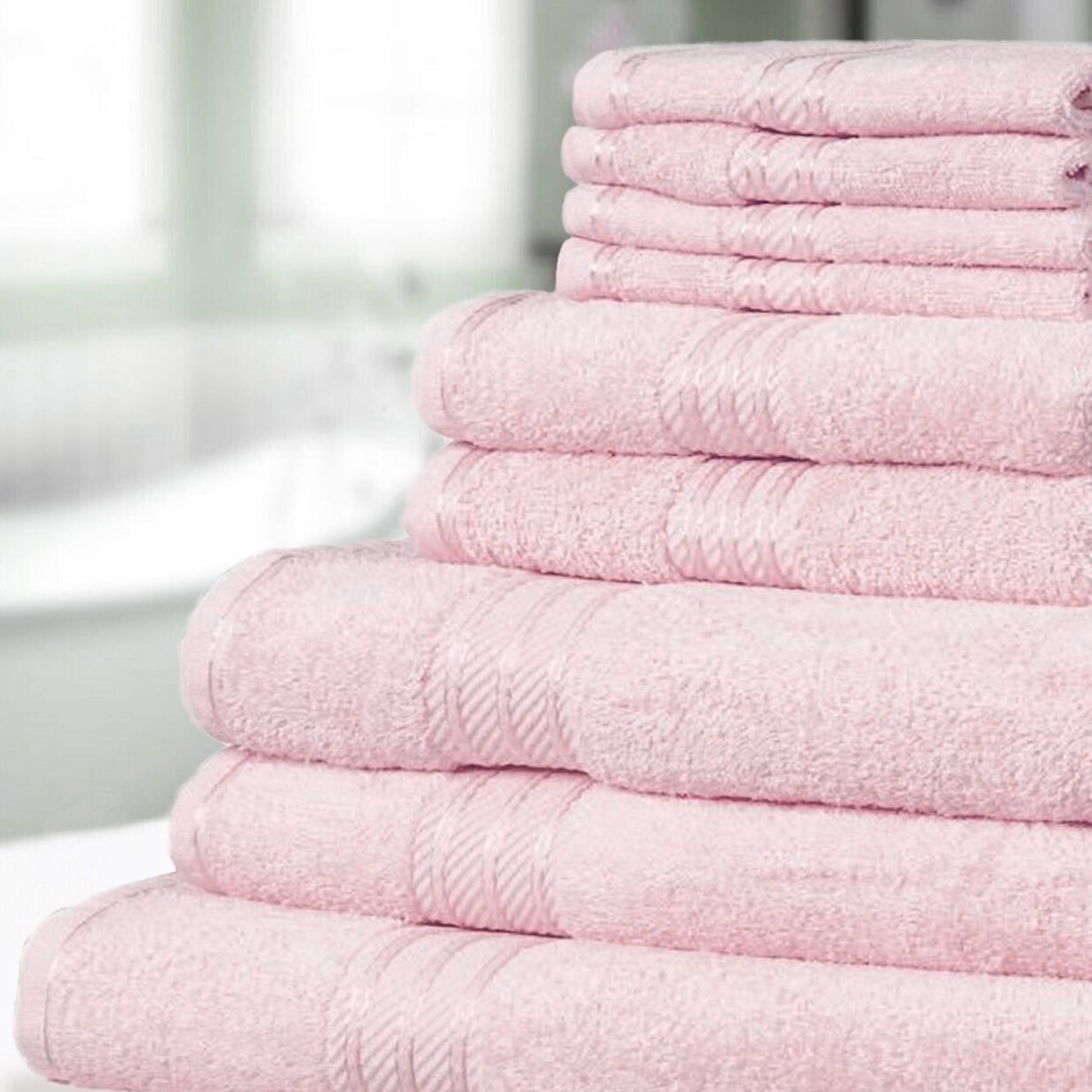 Stack of pastel pink bathroom towels on a blurred background