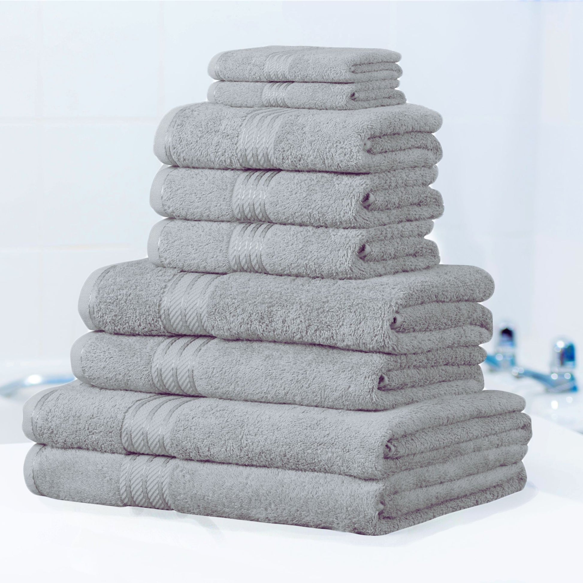 Stack of grey bath towels on a white surface with a blurred bathroom background