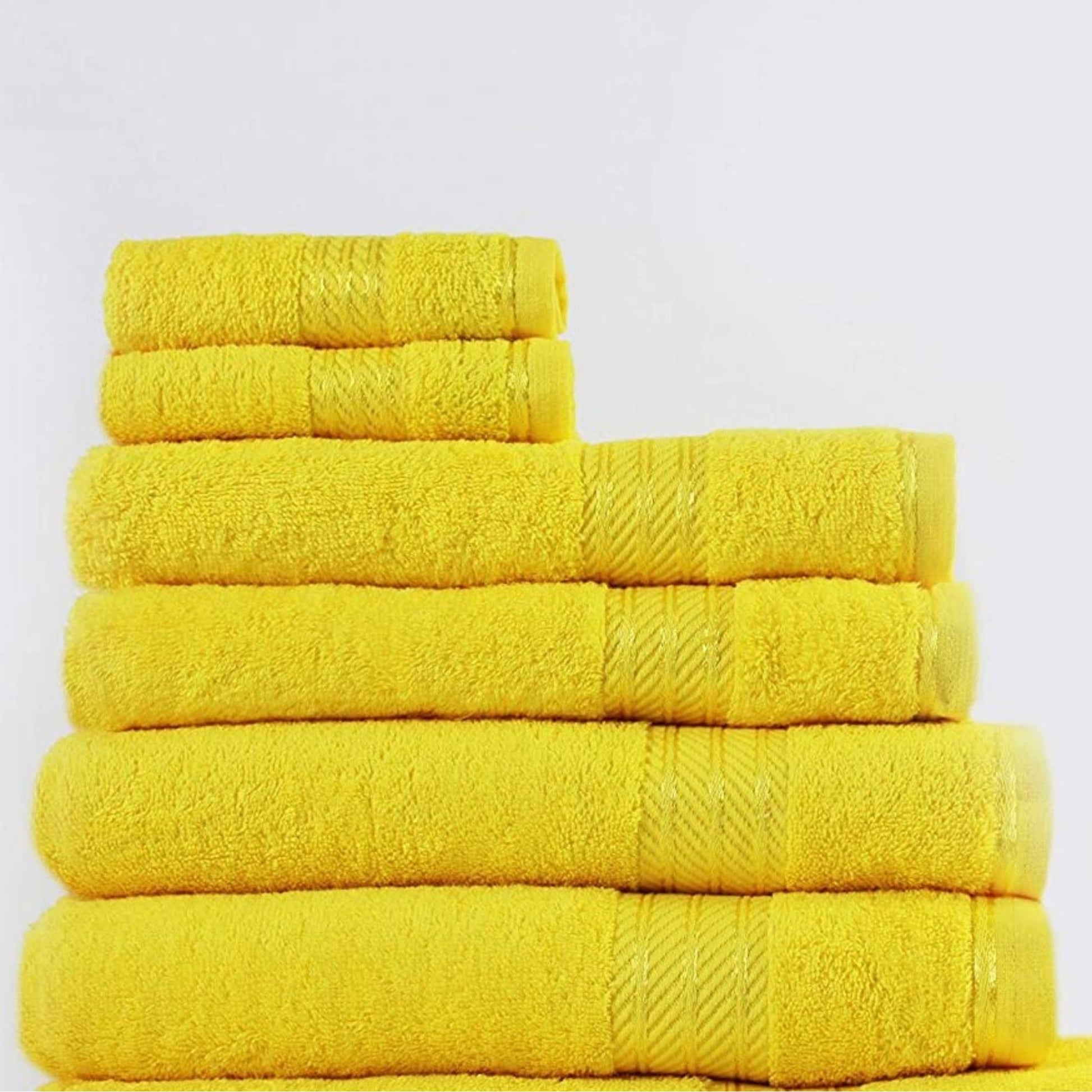 Stack of yellow bathroom towels on a light grey background
