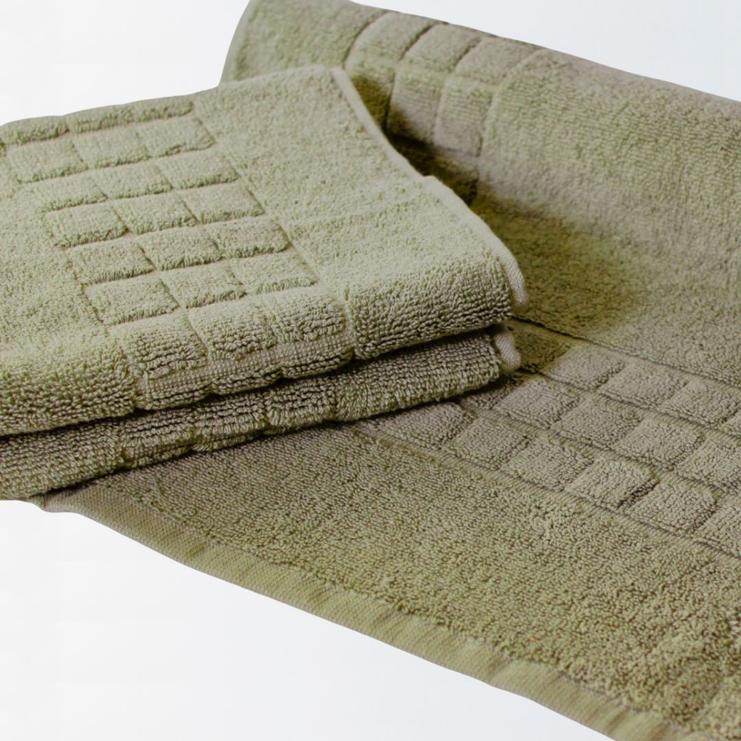 Folded sage green bath mat with textured pattern on a white background