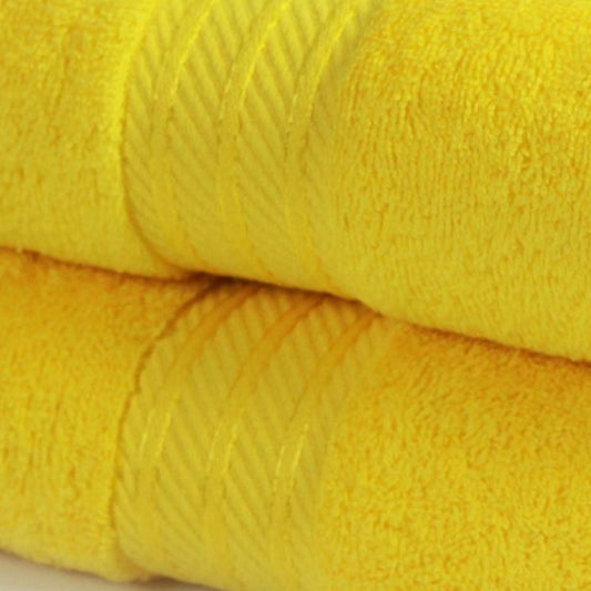 Two yellow bath towels stacked on a white background